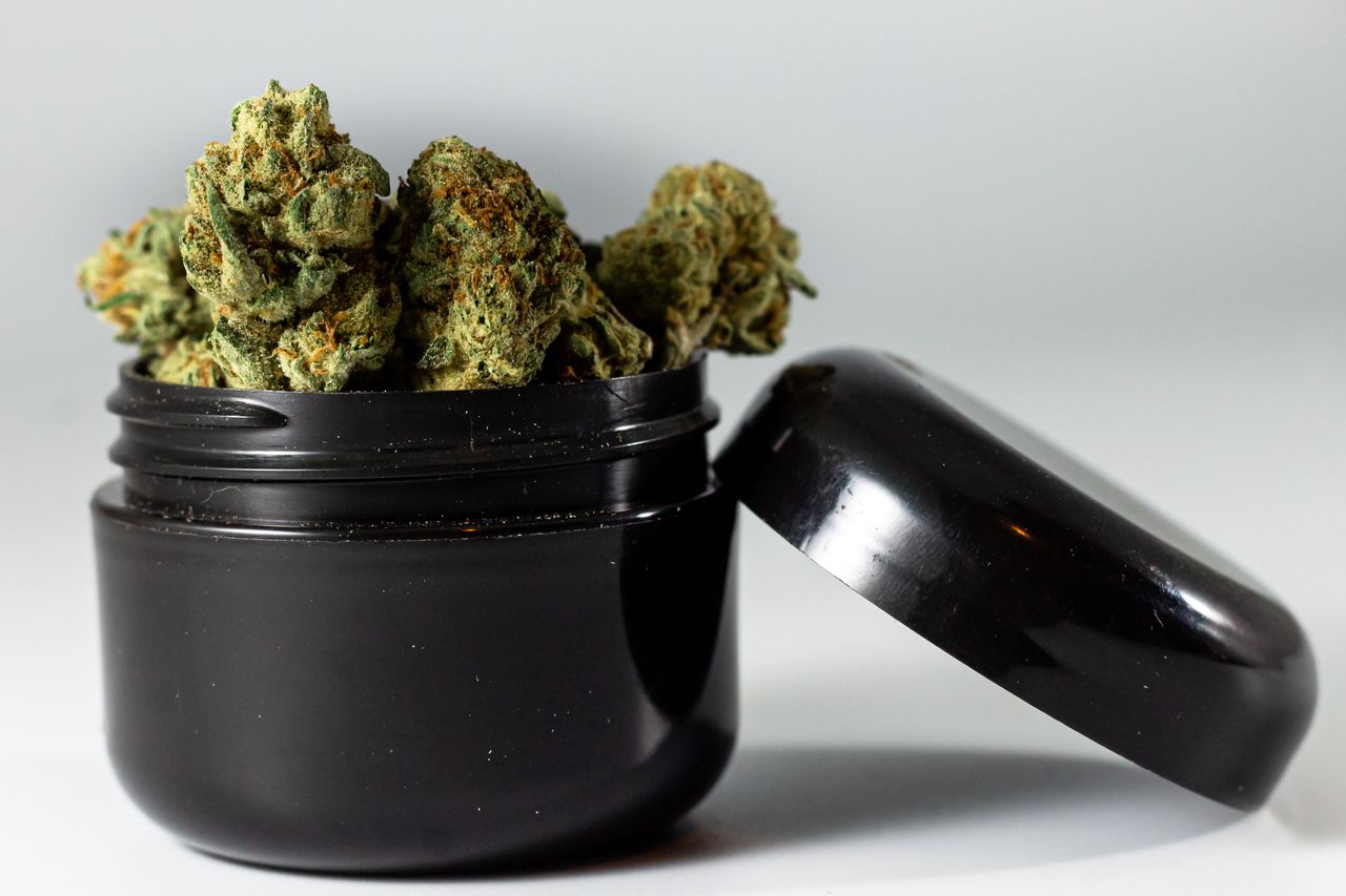 The Art of Drawing Readers In: Your attractive post title goes here Detailed image of cannabis buds overflowing from a black jar, showcasing texture and color.